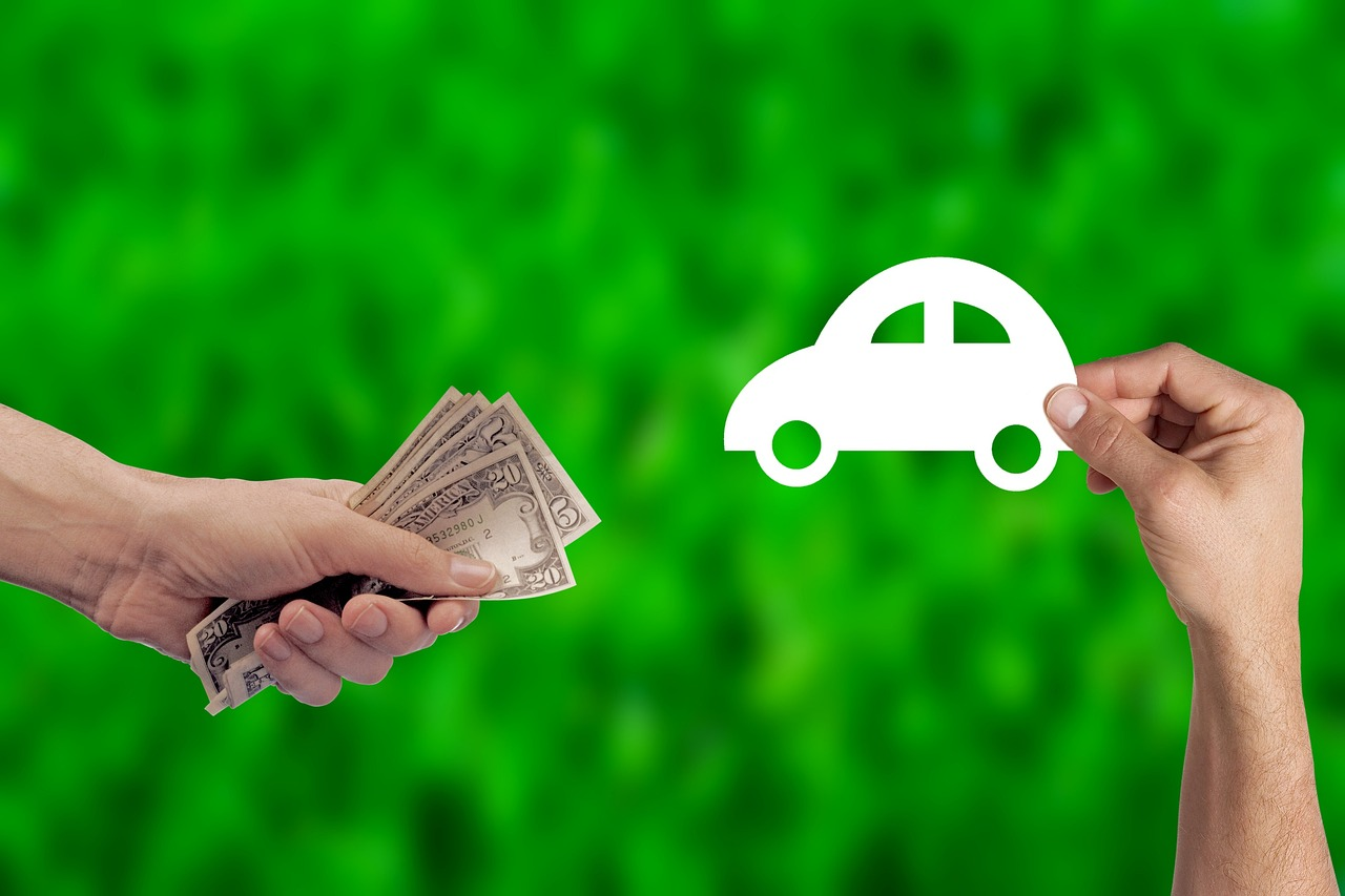 picture of a hand holding dollar bills, another holding a paper cutout of a car next to it